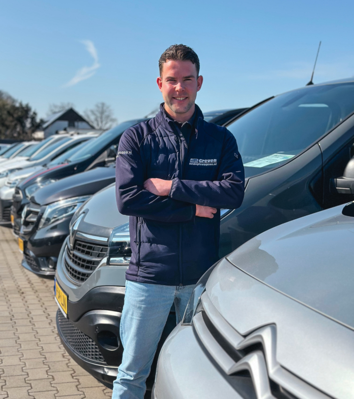 Medewerker van Greven Automotive die met gekruiste armen voor een rij bedrijfswagens staat op het terrein van Greven Bedrijfswagens.